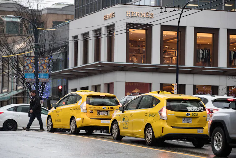 Yellow taxis wait in traffic in front of the Hermès store in downtown Vancouver