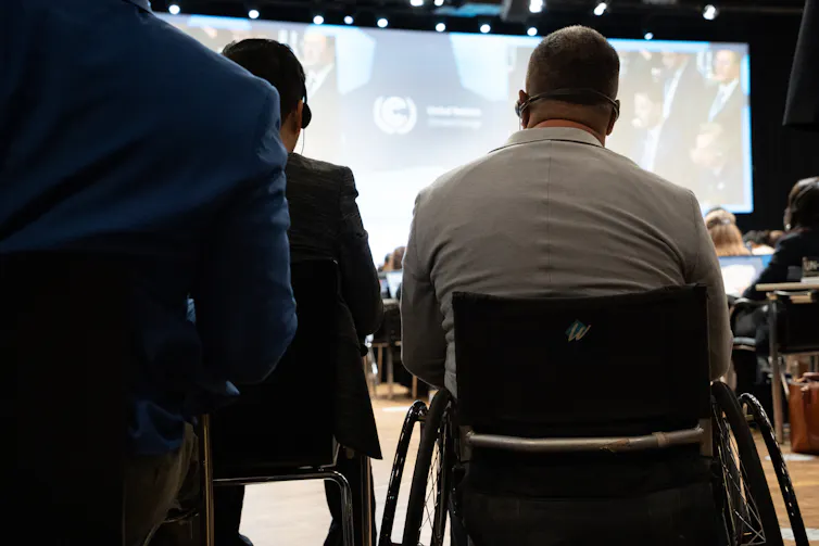 back view of man sat in wheelchair looking towards presentation in meeting room