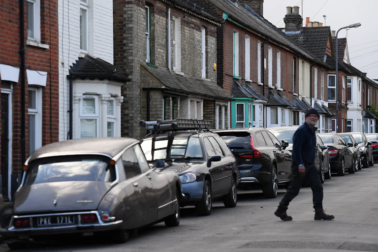 working class street of terraced homes with a man crossing the road in the foreground.