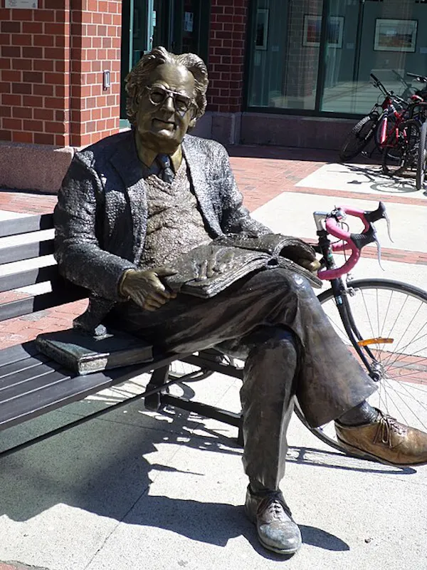 Statue of a man sitting on a park bench.