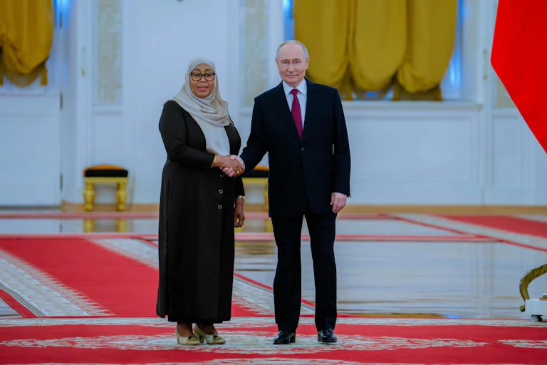 A woman wearing a headscarf shakes hands with a man in suit and tie