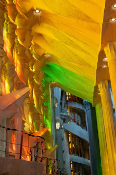Multi coloured light shine through a stained-glass window into a church.
