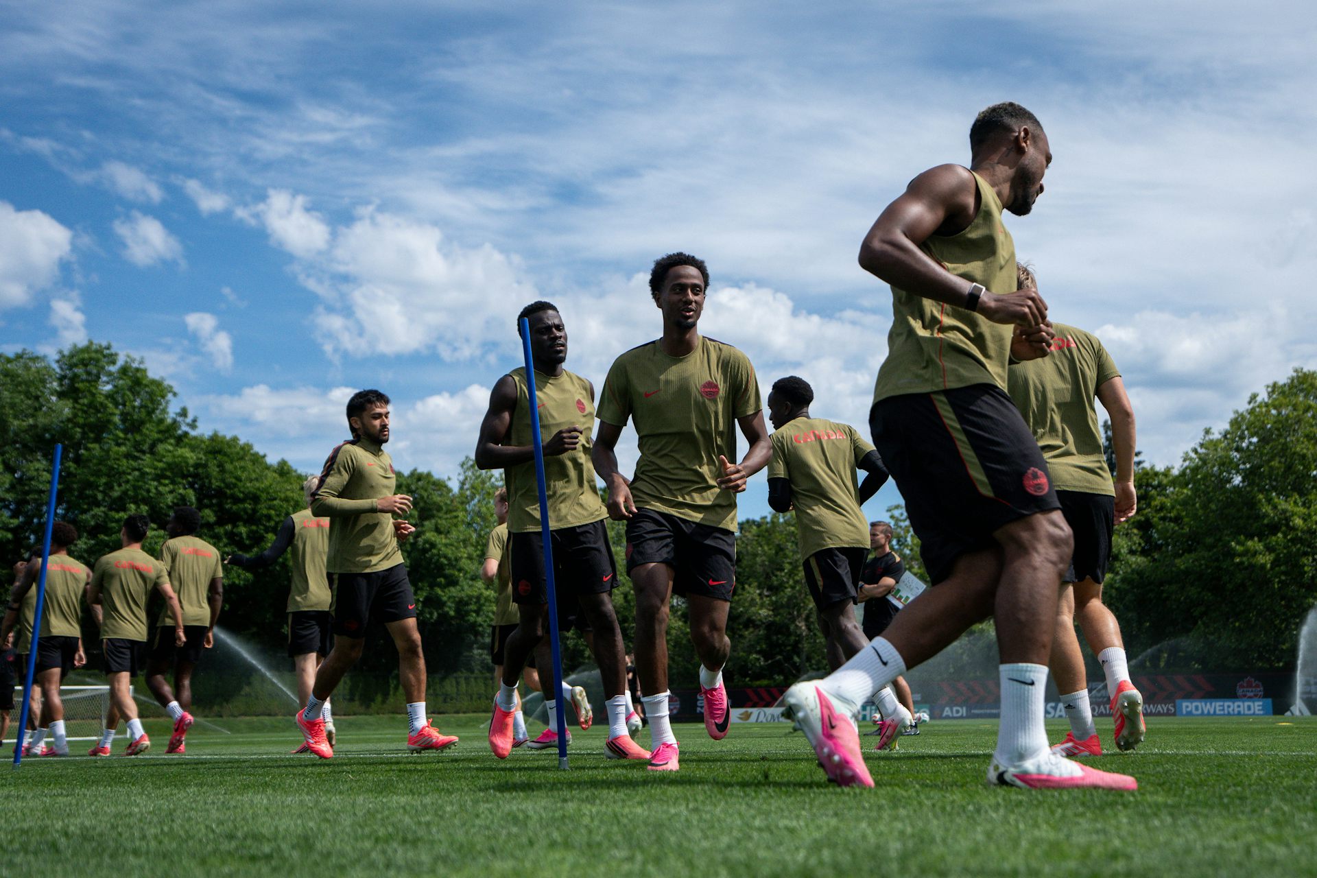 Several men, most of them Black, practise on a soccer pitch.