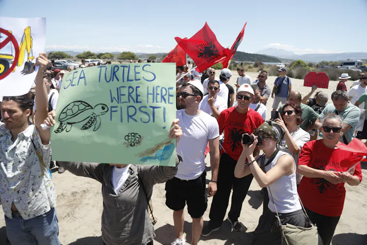 Protestors hold a banner reading 'sea turtles were here first!' in the area planned for a coastal resort project.