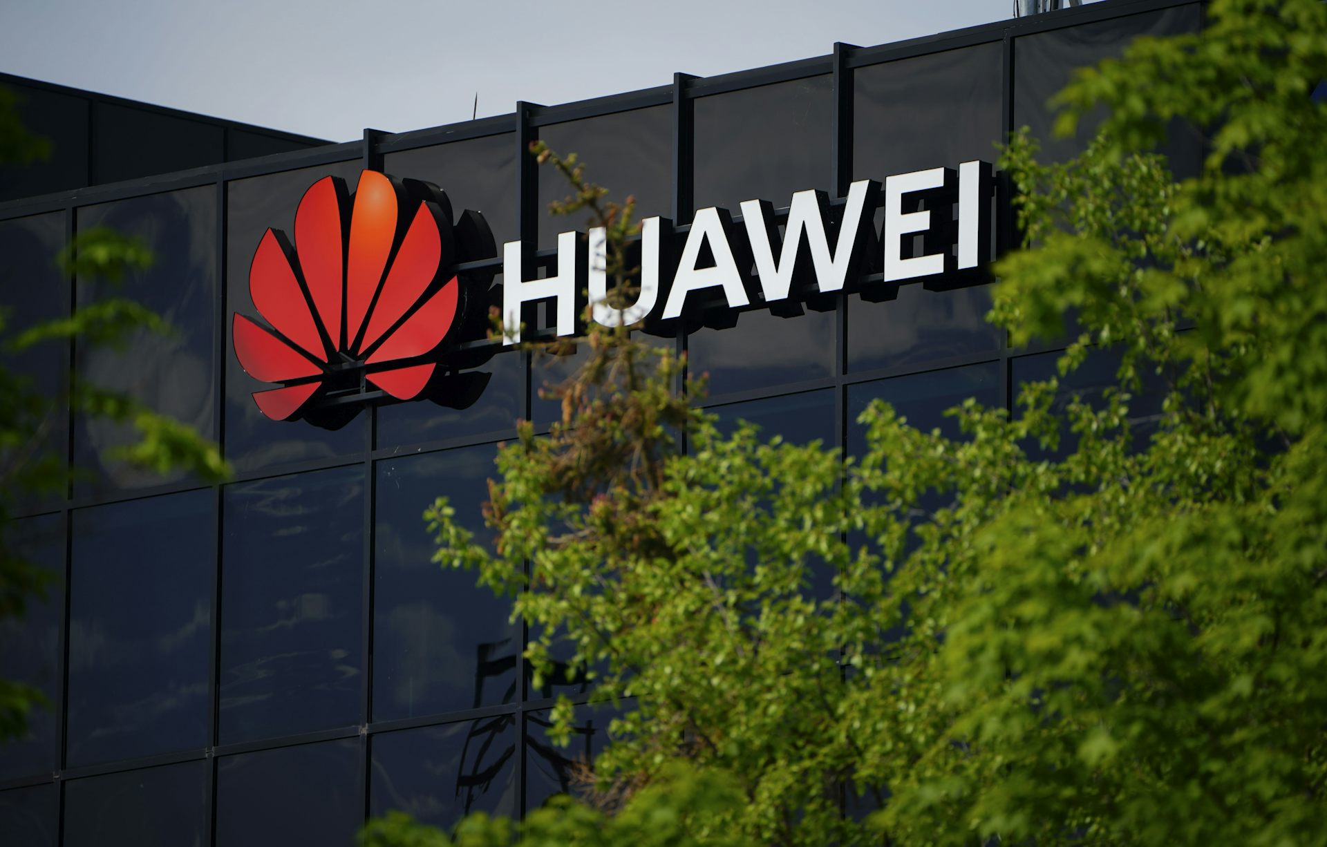 Logotipo de Huawei en un edificio enmarcado por árboles