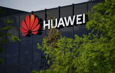 Logotipo de Huawei en un edificio enmarcado por árboles