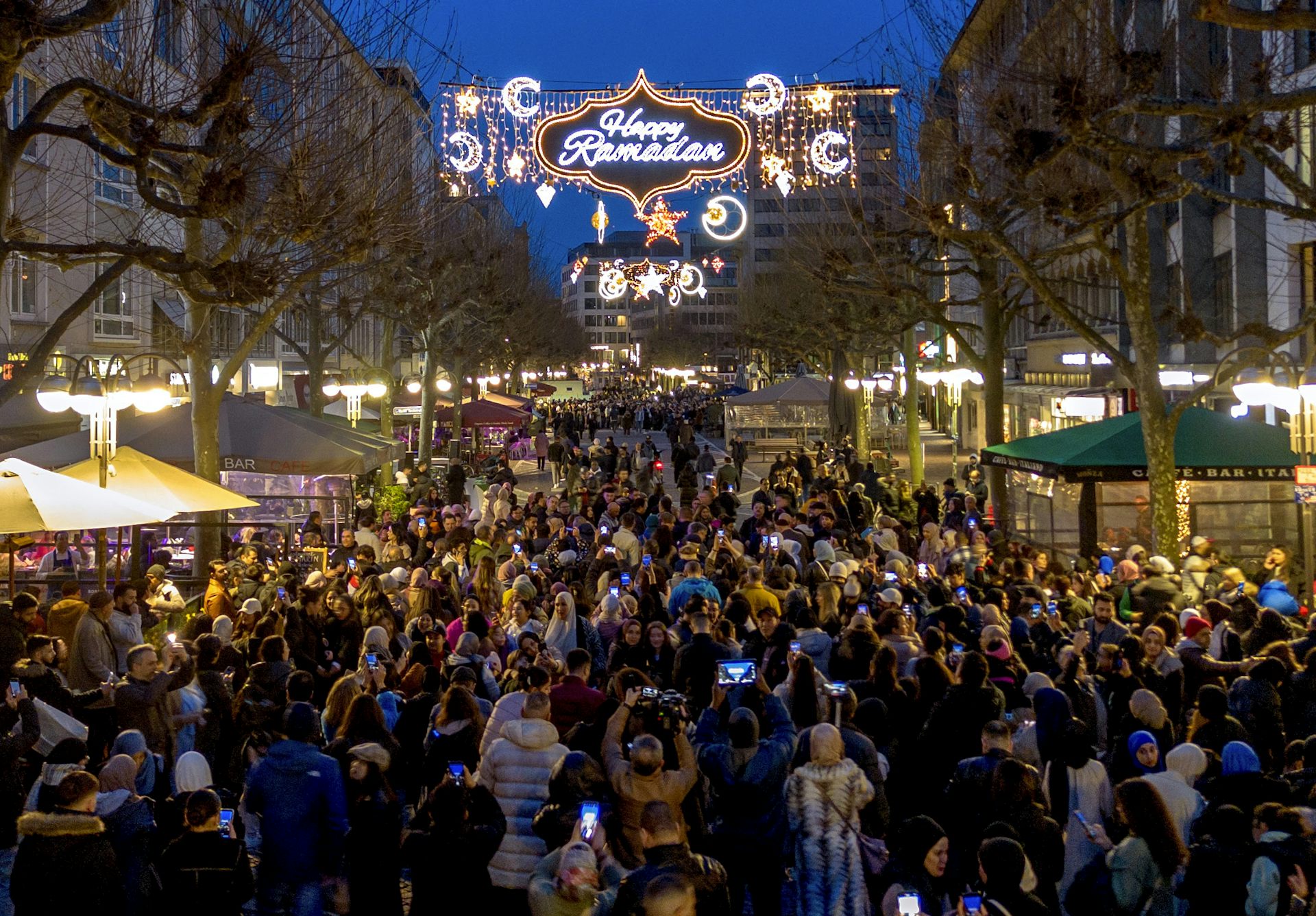 una gran multitud de personas camina entre los puestos de la calle peatonal