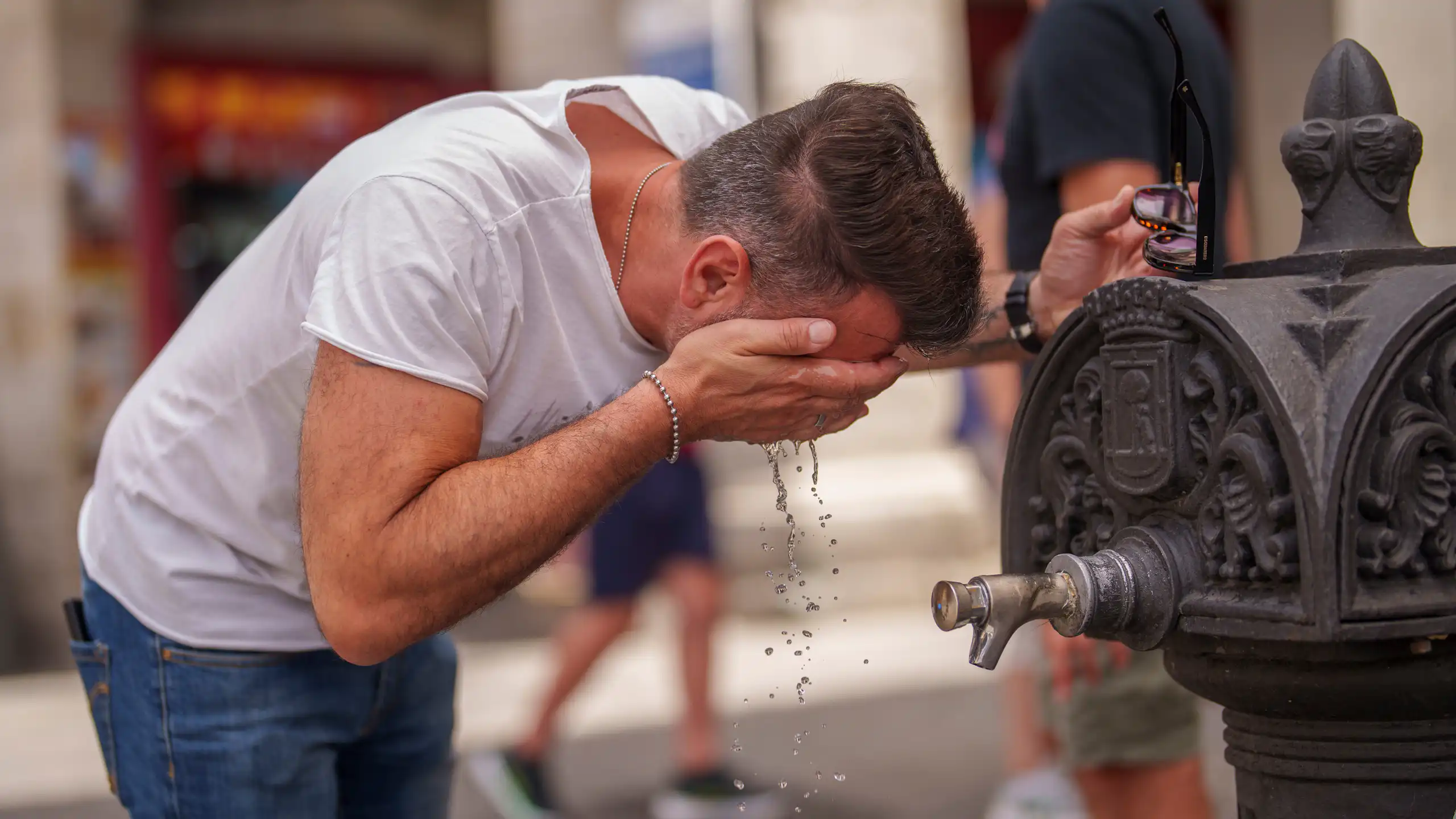 A man cools off in a fountain during a hot day in Madrid, Spain.