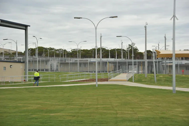 Lawns and streetlights in front of a grey concrete detention centre