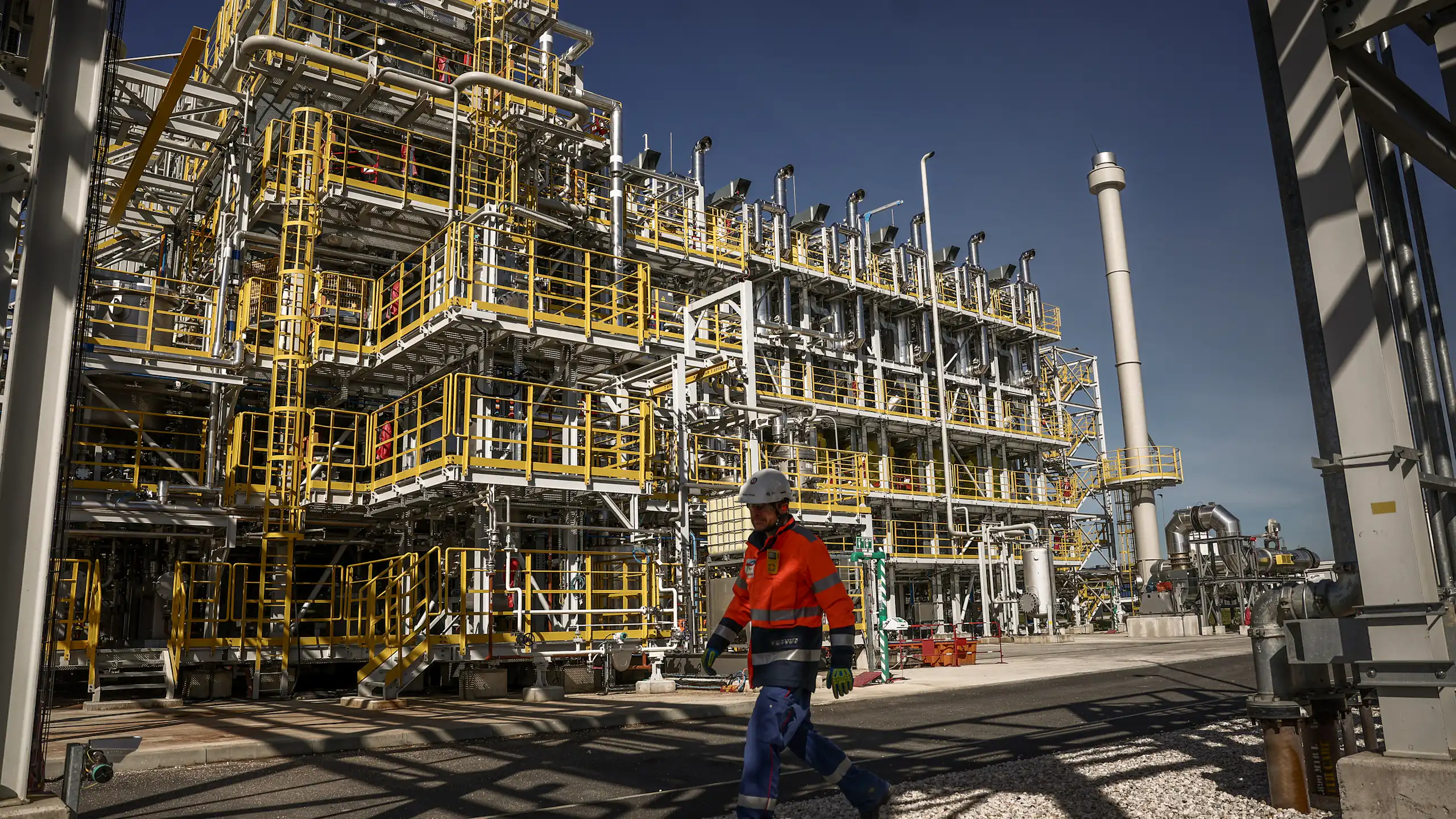 On voit un ouvrier de maintenance passant devant les unités de production.