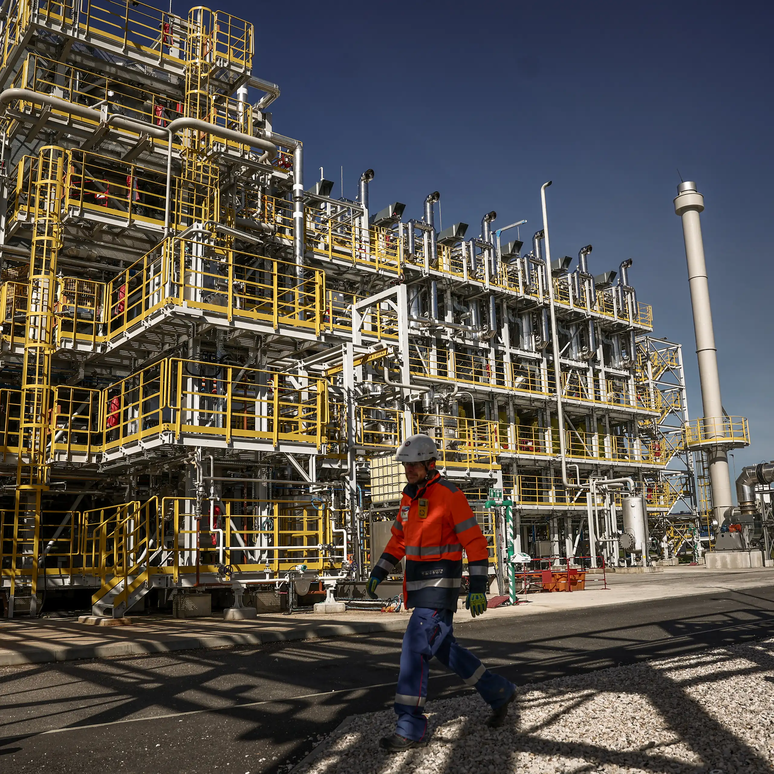 On voit un ouvrier de maintenance passant devant les unités de production.