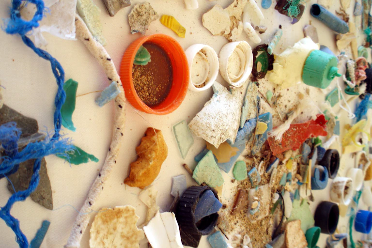 Sur une table, toutes sortes de déchets plastiques : des bouchons de toutes les formes, des tuyaux, des cordes…