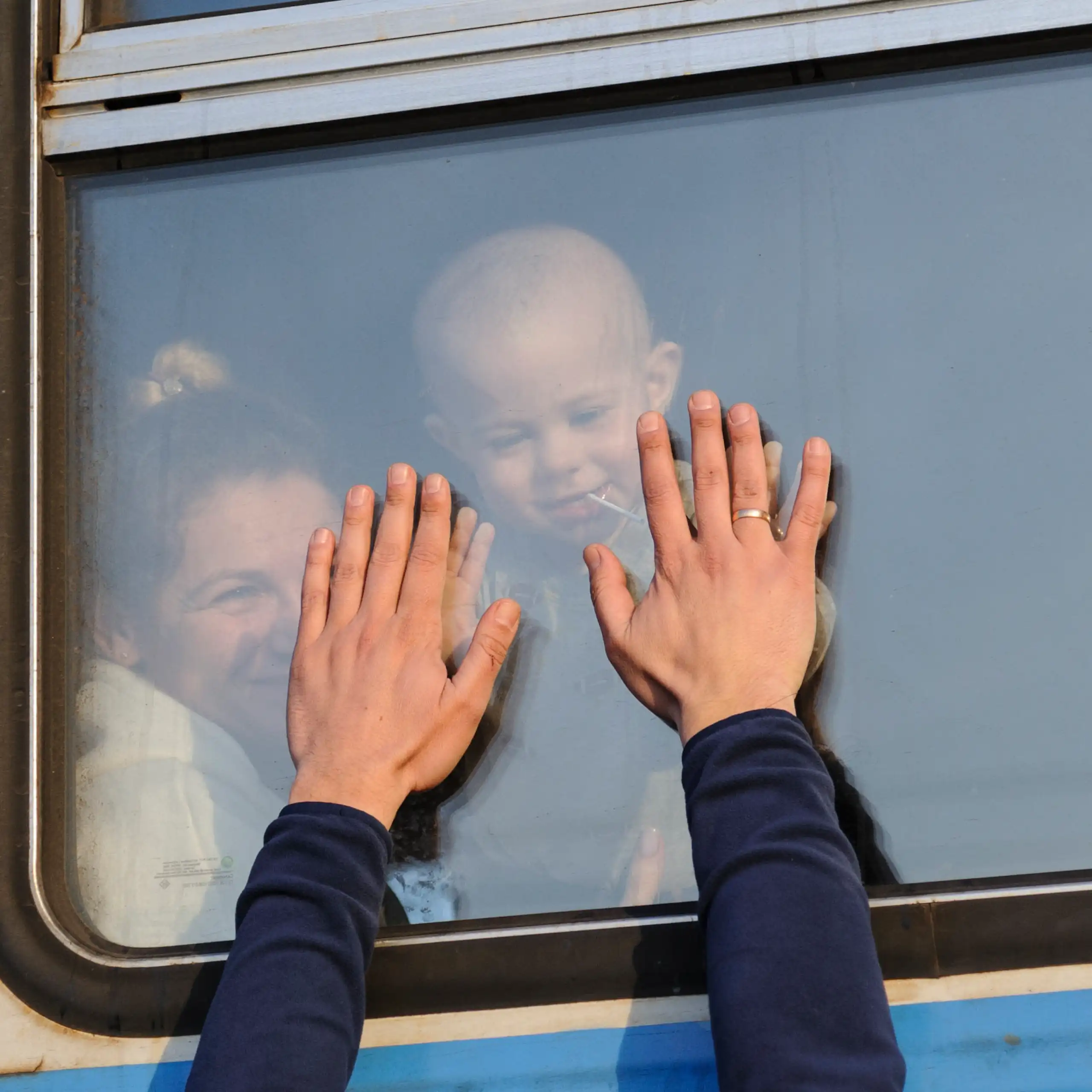 Ukrainian refugees wave goodbye as they depart on a train.