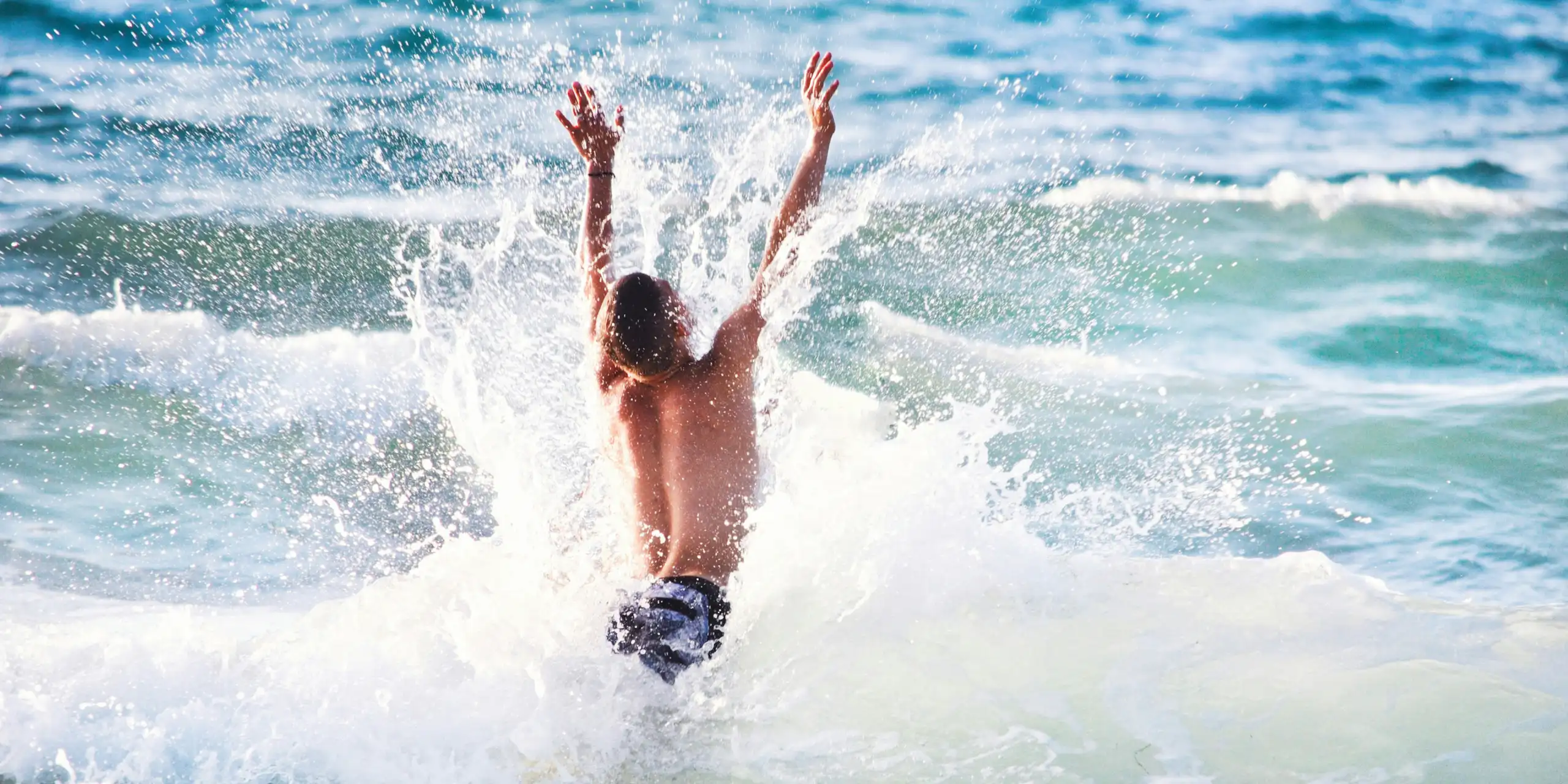 Photo d’un adolescent en train de sauter dans les vagues