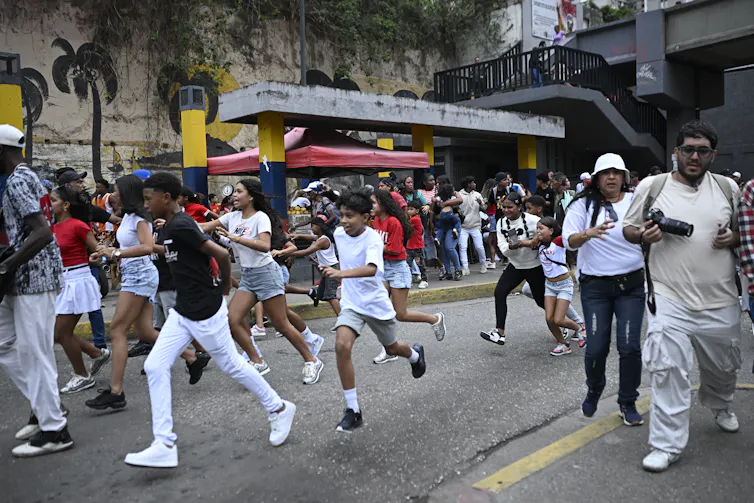 Many people run from the doors of a building into the street.