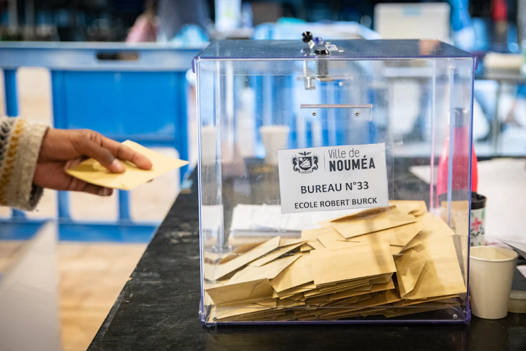 image d'une urne et d'une main déposant un bulletin de vote