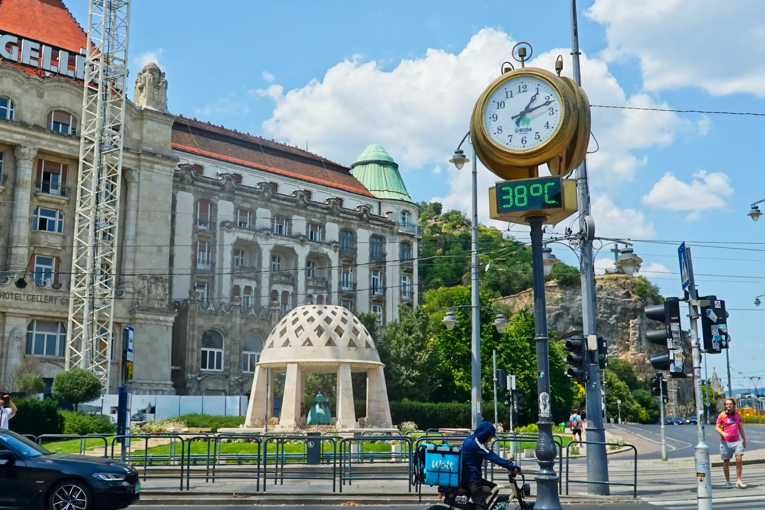 A large clock and thermometer in a city square during an intense heatwave. The thermometer reads 38 °C.