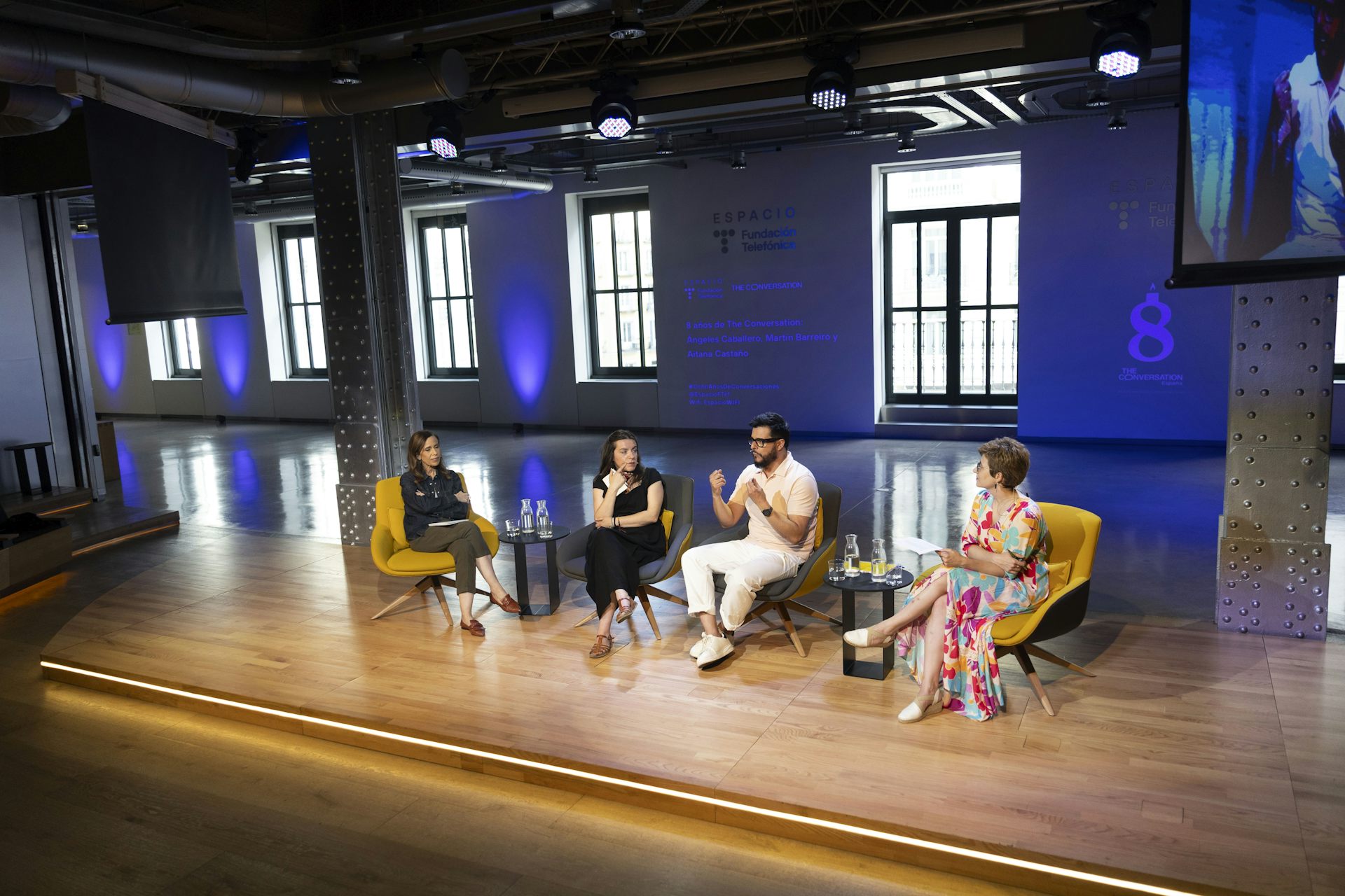 Cuatro personas charlan sentadas sobre un escenario. 