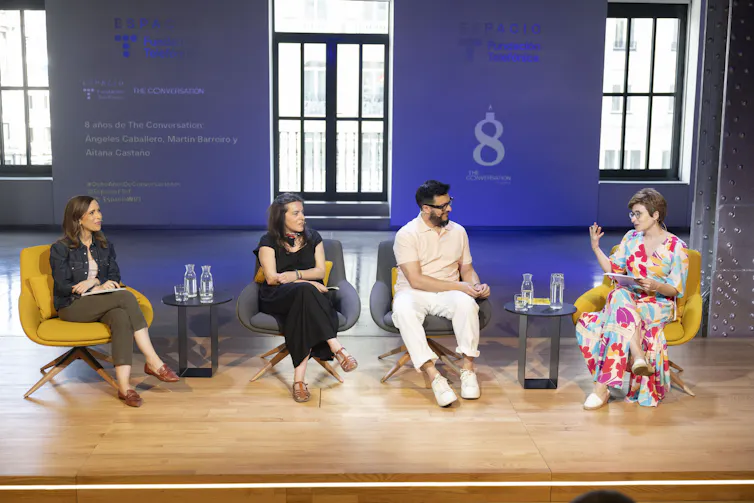 Cuatro personas hablan en el escenario.