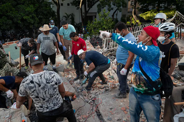 Um grupo de venezuelanos vasculha os escombros após dois terremotos.