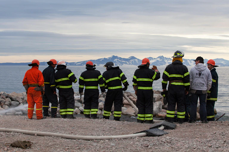 Firefighters in Greenland look across a bay towards mountains