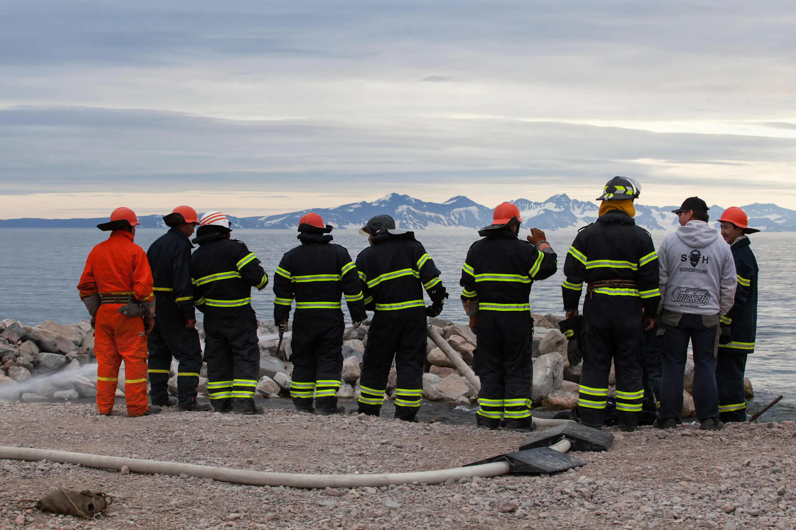 Firefighters in Greenland look across a bay towards mountains