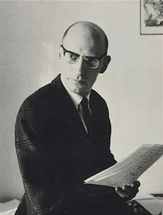 Michel Foucault wearing glasses and holding printed pages.