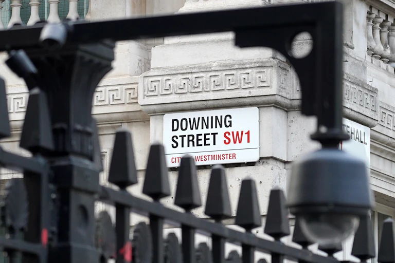 downing street street sign viewed through some black railings.