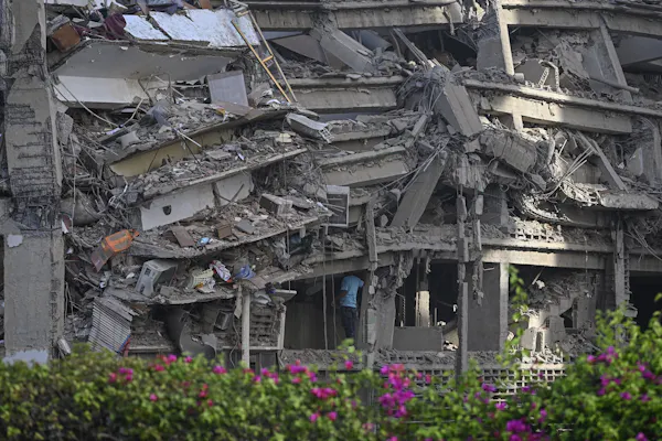 A man in a blue t-shirt enters a crumbling building.