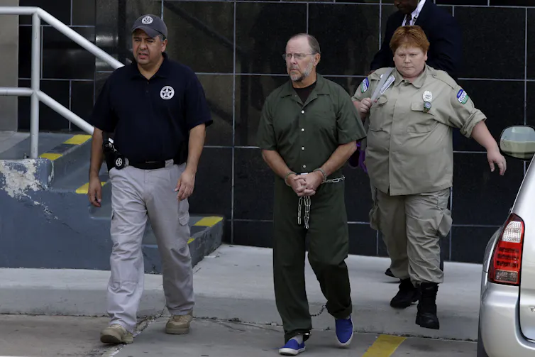 Former Enron CEO Jeffrey Skilling, with a beard and glasses, is escorted by guards from a federal courthouse on June 21, 2013, after being resentenced for his role in the energy giant's collapse.