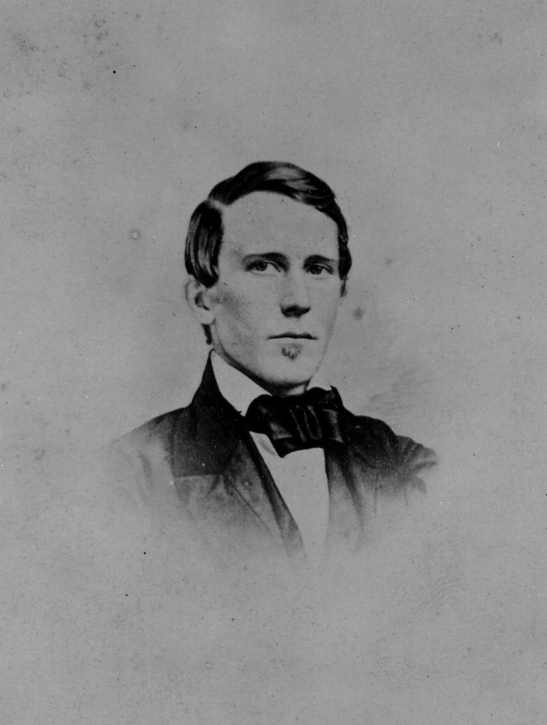 A portrait of a young man with a comb-over, pursing his lips.