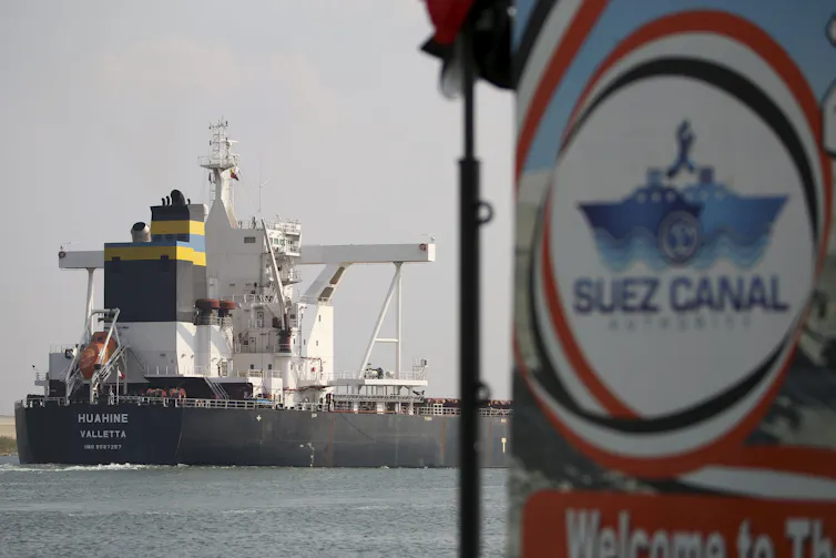 A ship on water behind a Suez Canal Authority sign.
