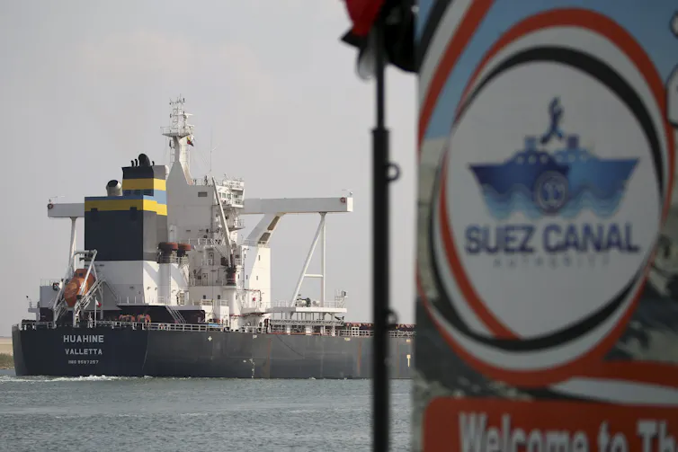 A ship on water behind a Suez Canal Authority sign.