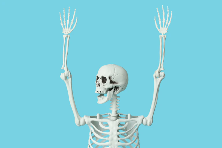 Skeleton with arms raised against a blue background.