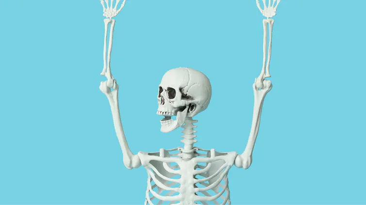 Skeleton with arms raised against a blue background.