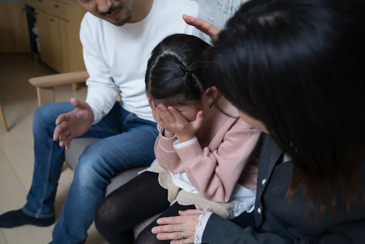 A sad child being comforted by her parents