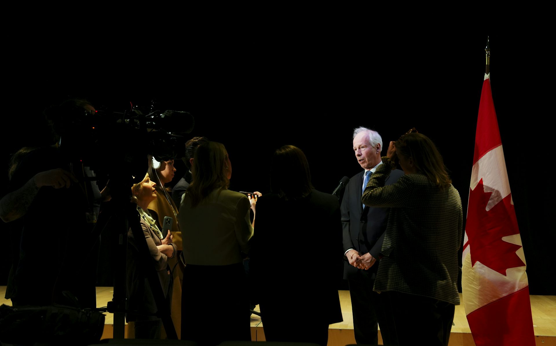 Stéphane Dion debout, au micro, avec un drapeau canadien en arrière-plan.
