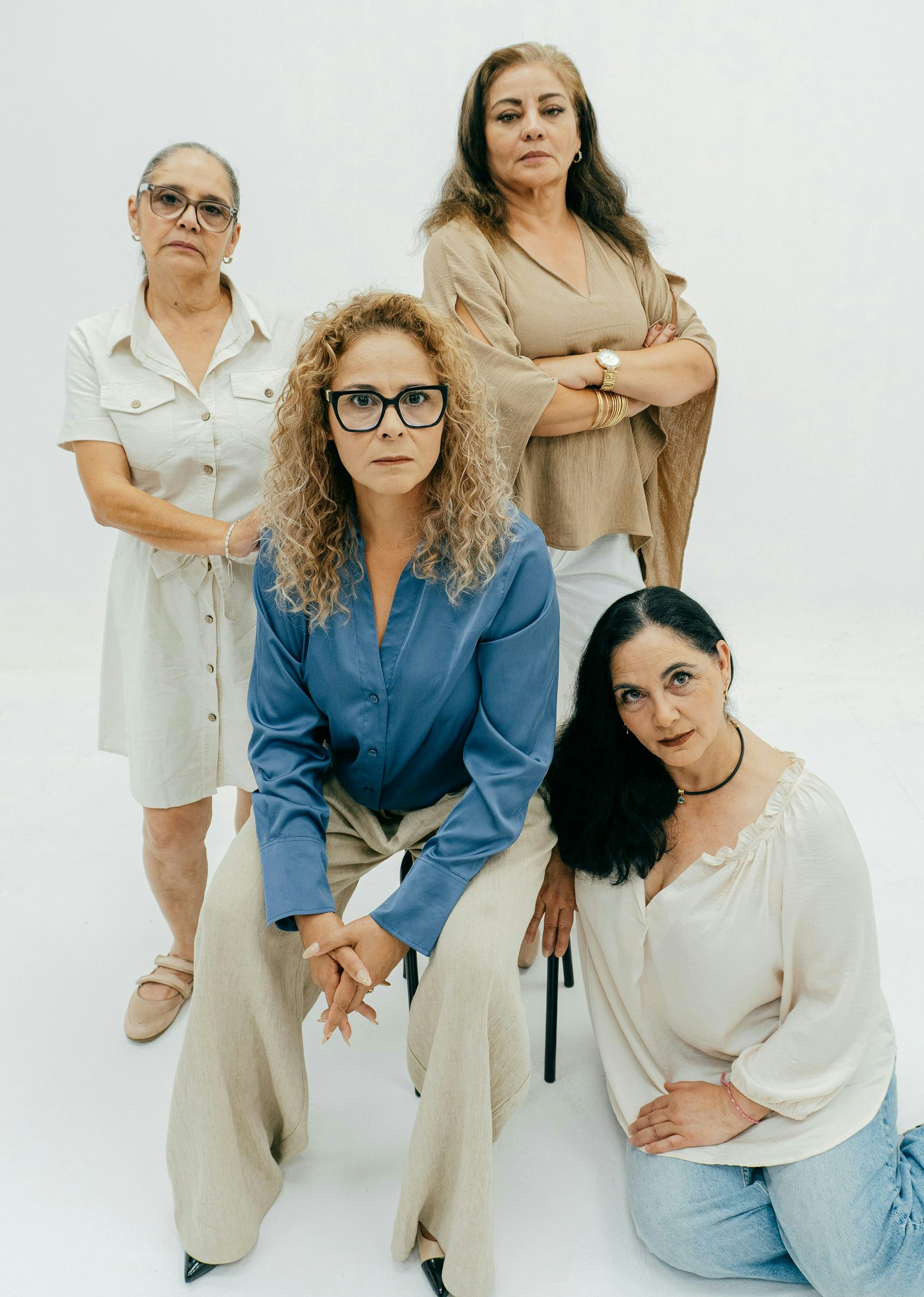 Un grupo de mujeres, algunas sentadas en sillas y otras de pie, observando.