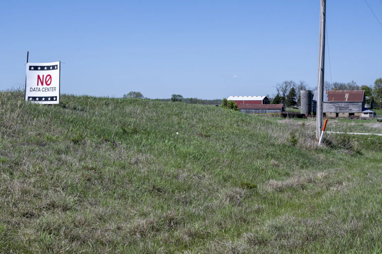 A view of open grassland with a barn and a sign reading 'No data center.'