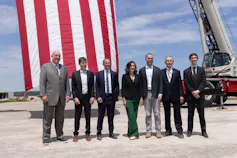 A group of people stand together on a piece of bare ground.
