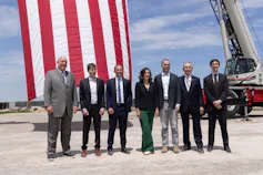 A group of people stand together on a piece of bare ground.