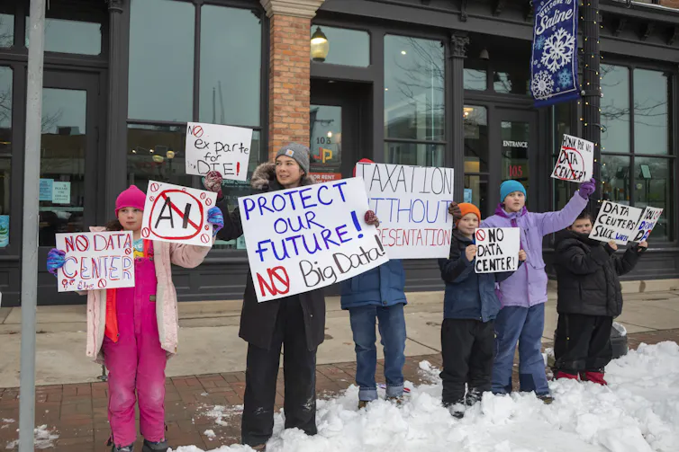 People bundled up against winter cold hold signs saying 'No data center' and 'Protect our future - no big data.'