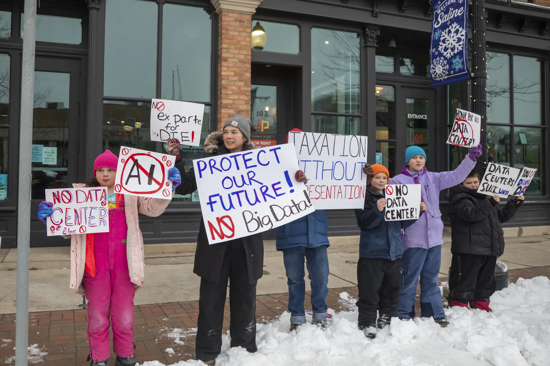 People bundled up against winter cold hold signs saying 'No data center' and 'Protect our future - no big data.'