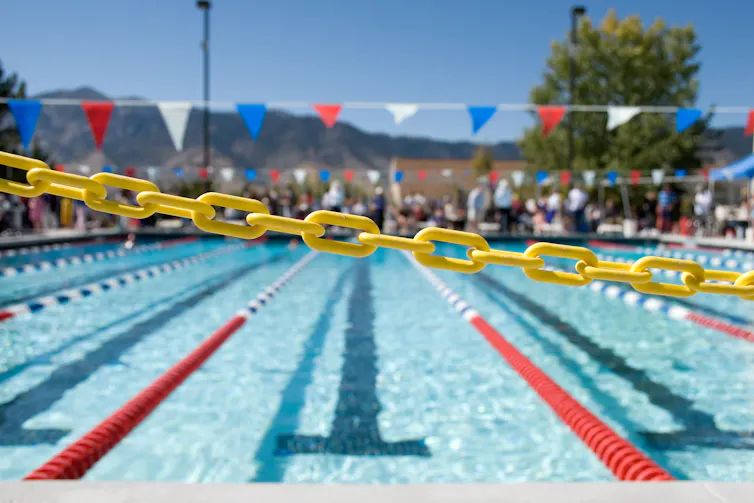 View across swimming pool at spectators standing and sitting on the other side