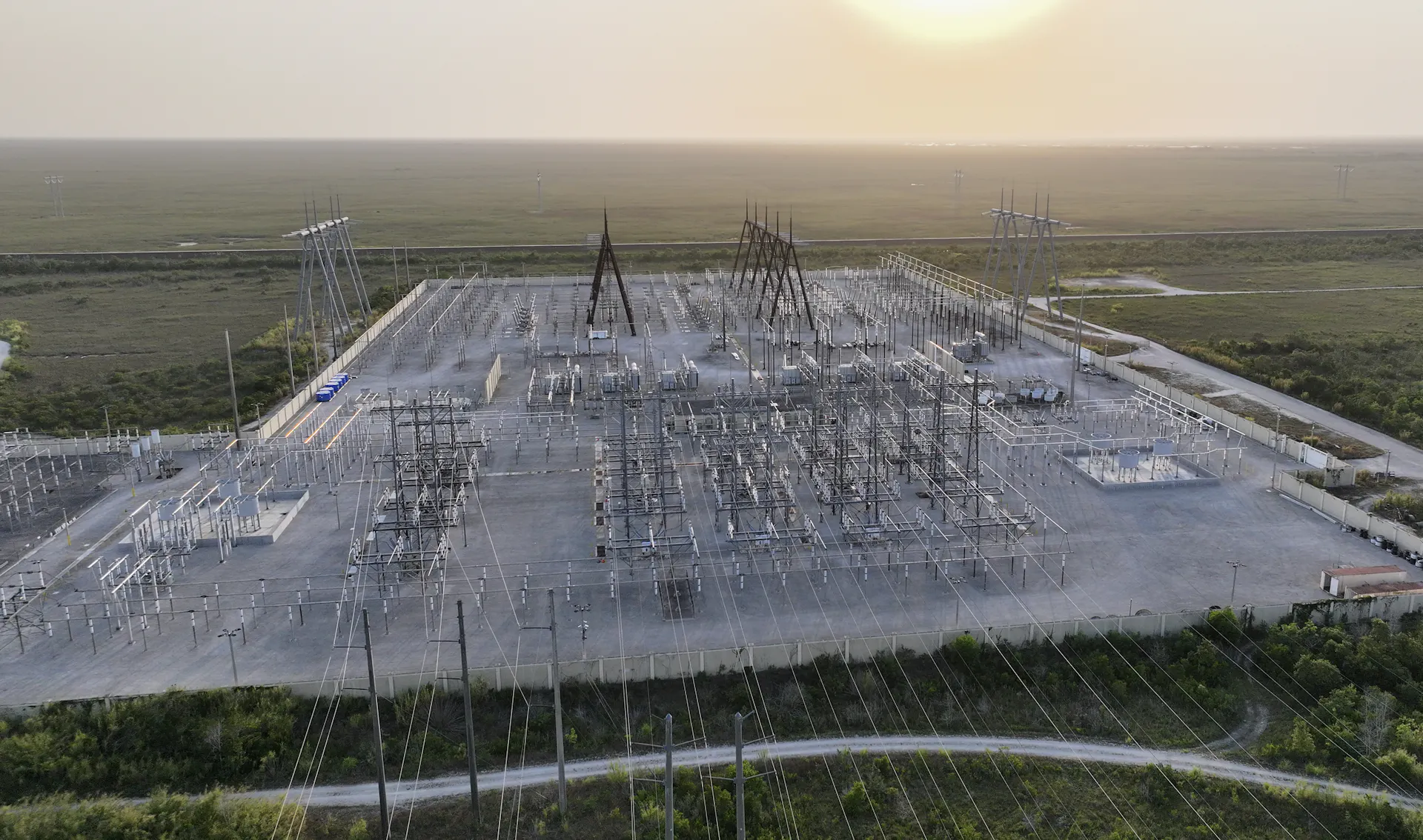 An aerial view of an area covered in wires, metal boxes and towers.