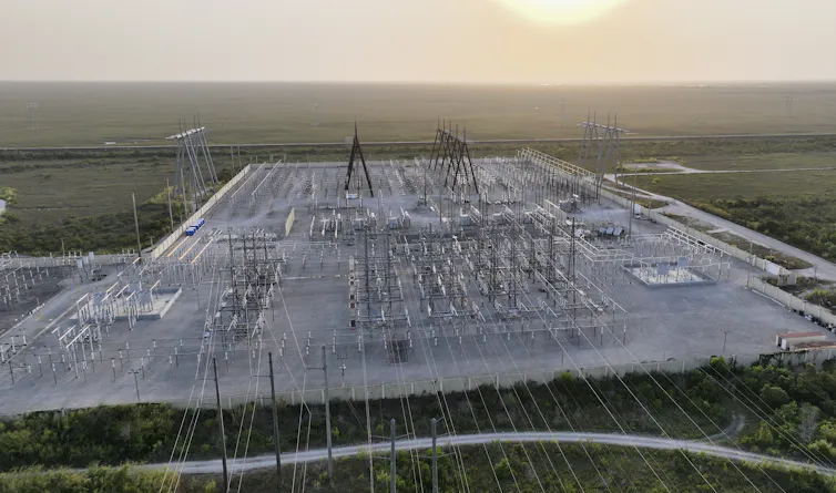 An aerial view of an area covered in wires, metal boxes and towers.