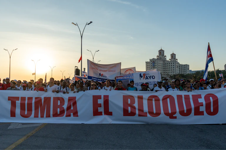 parade of people holding a sign that says 'Tumba El Bloqueo'