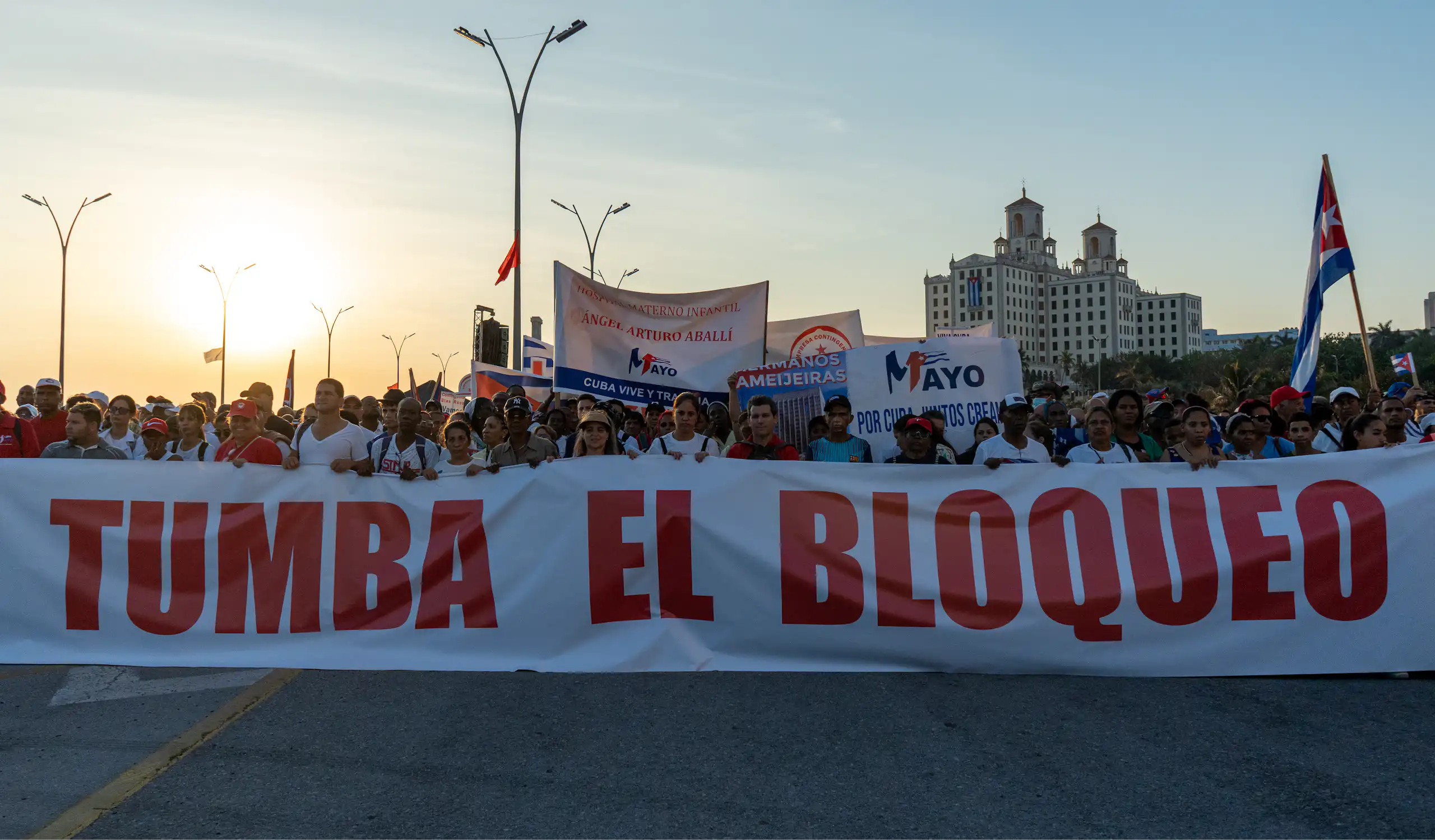 parade of people holding a sign that says 'Tumba El Bloqueo'