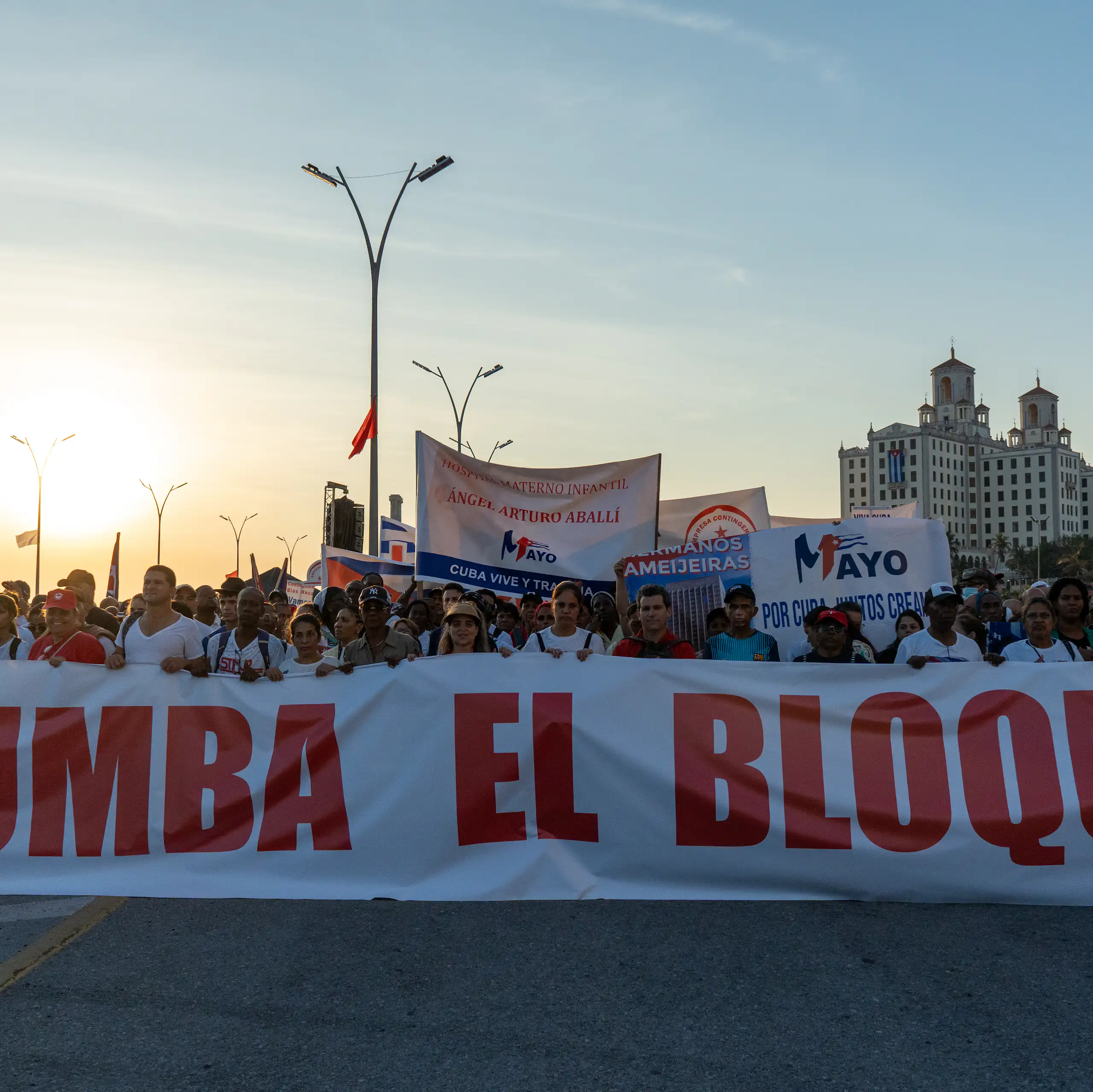 parade of people holding a sign that says 'Tumba El Bloqueo'