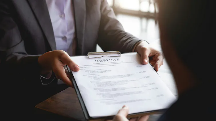 En qué se equivoca todo el mundo sobre la búsqueda de empleo moderna y qué realmente funciona 1 Una persona le entrega un currículum a alguien.